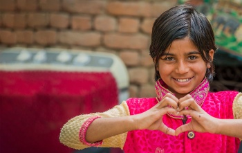 A girl in India makes a heart symbol with her hands