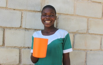 Tawina happily holding her cup of porridge