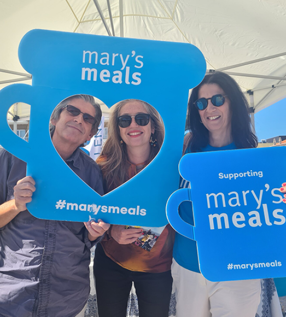 Mary's Meals volunteers and supporters holding signs. 
