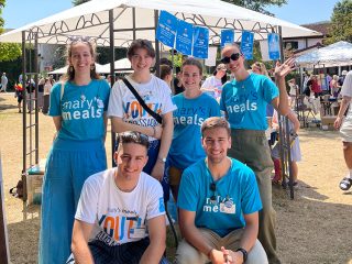 Young supporters and volunteers wearing Mary's Meals t-shirts posing for a photo at an event. 