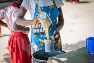 Volunteer pouring porridge for a child