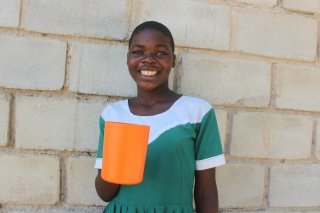 Tawina happily holding her cup of porridge